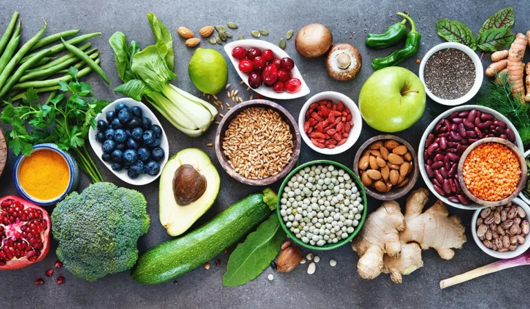 Assortiment de fruits, légumes, noix et graines sur une surface.